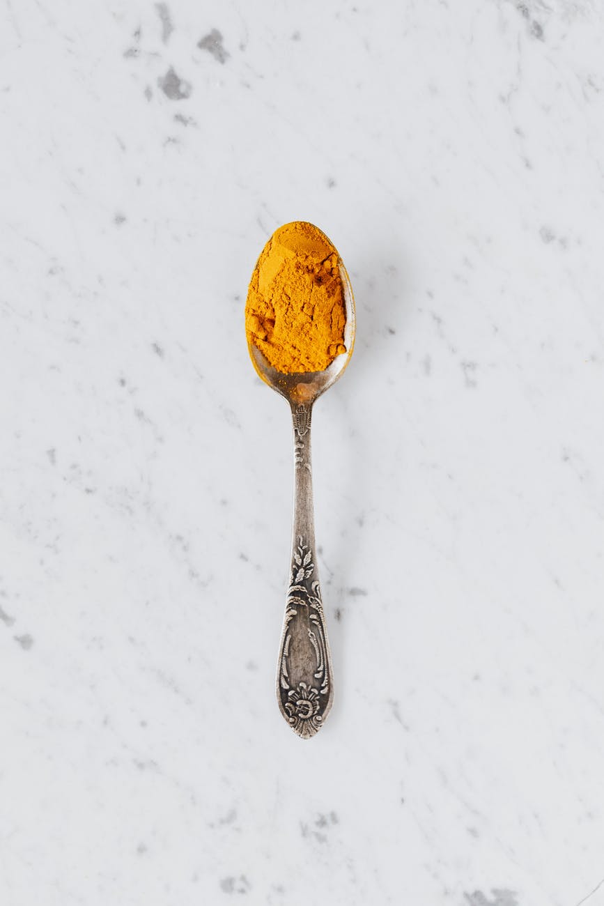 yellow turmeric powder in silver spoon